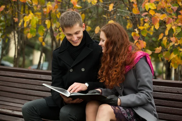 Mladý šťastný pár s knihou na lavičce — Stock fotografie