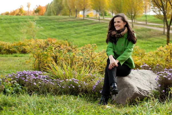 Young woman sitting in autumn park — Stock Photo, Image