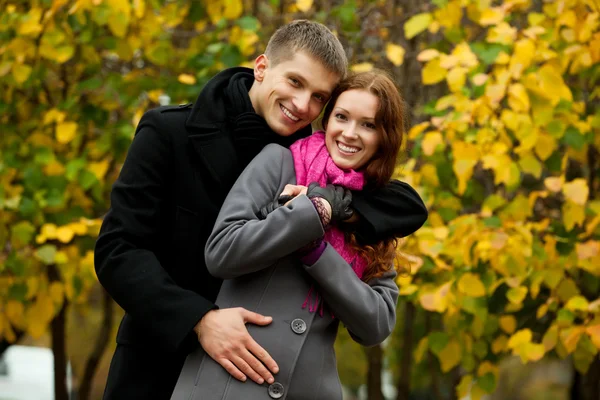 Молодой человек обнимает свою женщину, и они улыбаются — стоковое фото