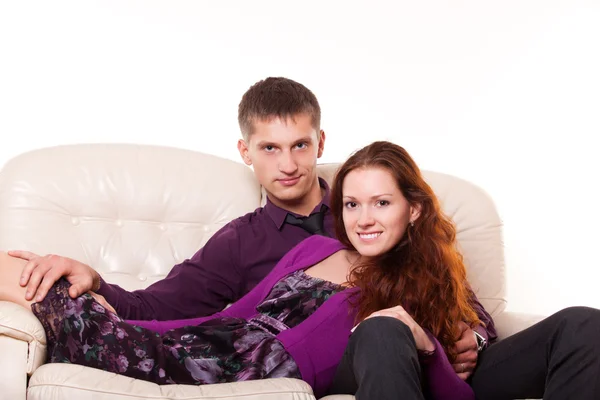 Beautiful young couple sitting on the couch — Stock Photo, Image