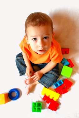 Baby plays with many-coloured toys clipart