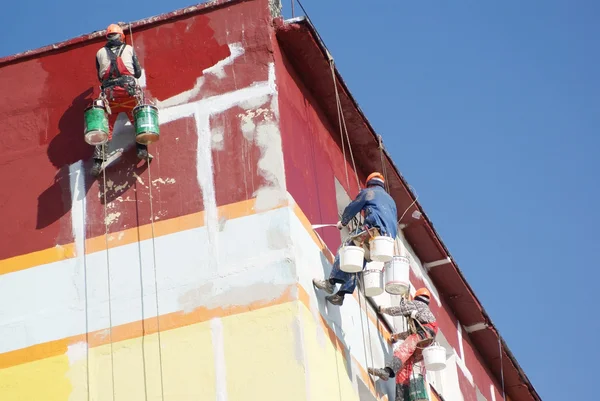 Steeplejacks painting the house against the blue sky — Stock Photo, Image