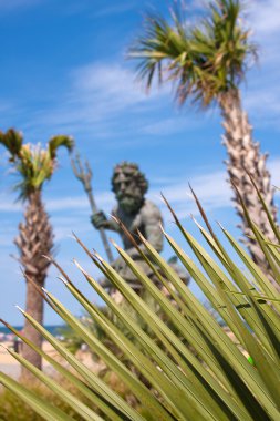 King Neptune Statue and Tropical Foliage clipart