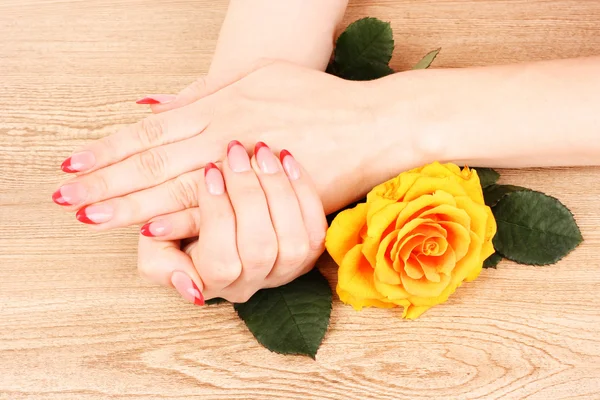 Hermosas manos de mujer y una rosa naranja — Foto de Stock