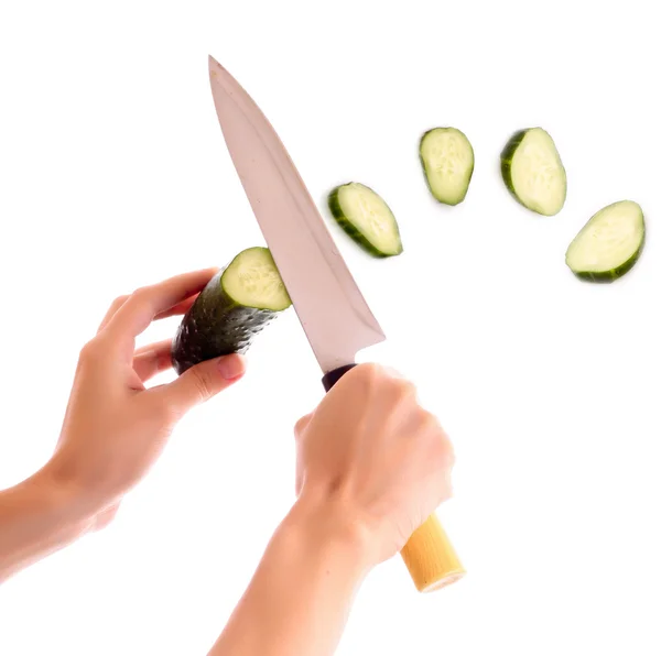 Someone cutting a cucumber, and slice flying isolated on white — Stock Photo, Image