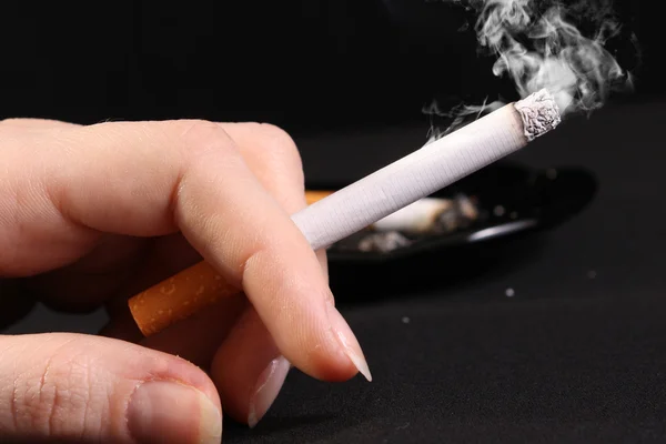 Frau hält Zigarette mit Rauch in der Hand — Stockfoto