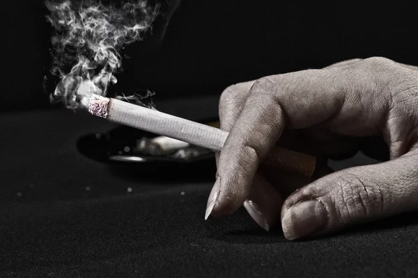 Alte Frau hält Zigarette mit Rauch in der Hand — Stockfoto