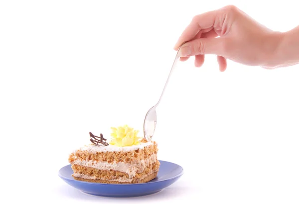 Mano con cuchara desprende una paz de pastel aislado en blanco — Foto de Stock