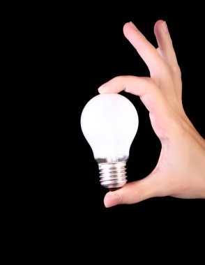 Incandescent bulb in hand isolated on black background clipart