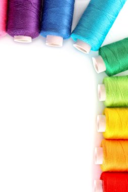 Pile of coloured bobbins of lurex thread isolated on white clipart