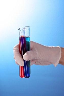 elinde mavi arka plan üzerinde test tüpü