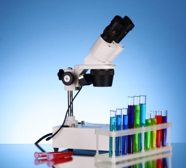 Laboratuvar metal mikroskobu ve test tüpleri ile sıvı mavi b