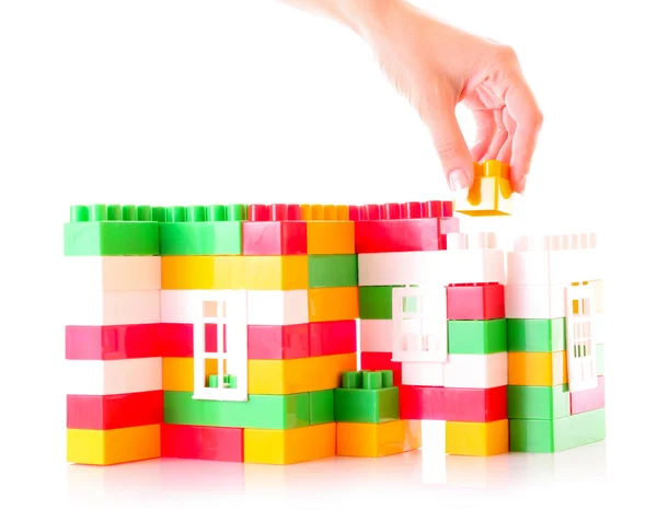 Mão adicionar tijolo de brinquedo para construção de brinquedos isolados em branco — Fotografia de Stock