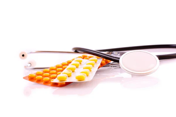 Stethoscoop en tabletten geïsoleerd op wit — Stockfoto