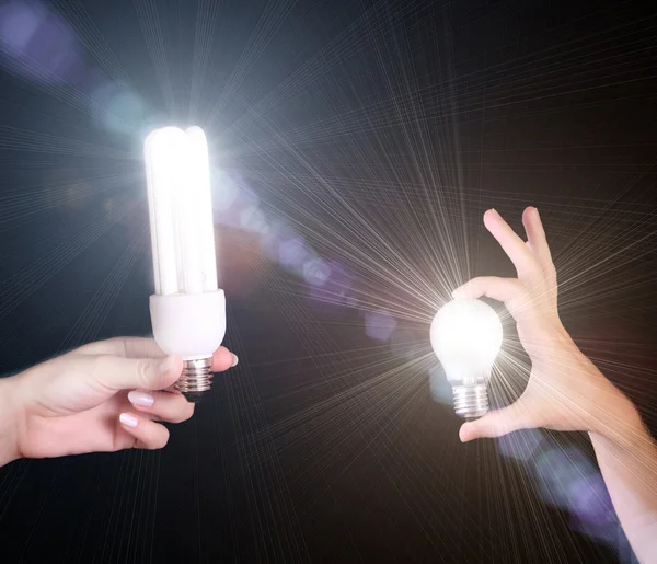 Two differrent light bulbs in hands isolated on black background — Stock Photo, Image