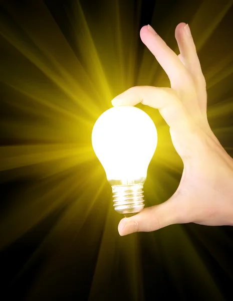 Bright yellow incandescent bulb in hand isolated on black backgr
