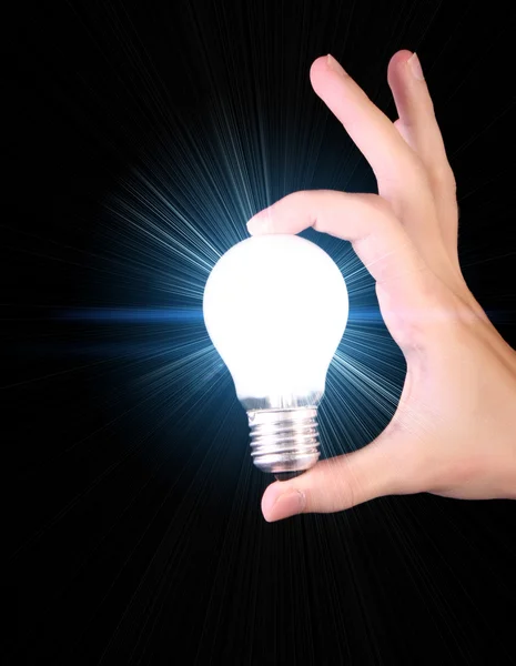 Bright incandescent bulb in hand isolated on black background