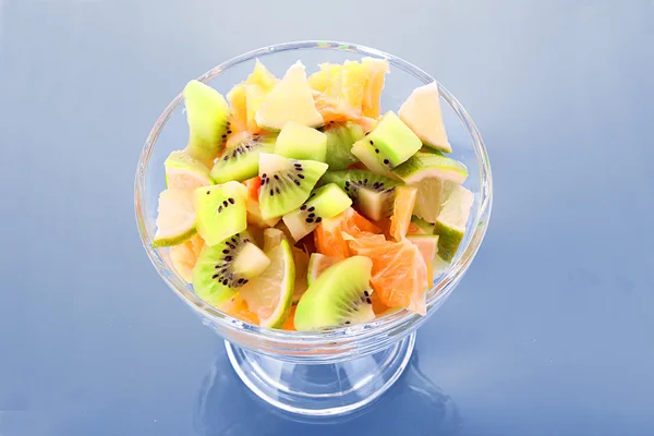 Cup with orange, kiwi and lime on blue — Stock Photo, Image