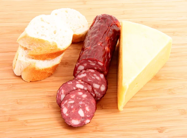 Sausage, bread and cheese on wooden plate — Stock Photo, Image