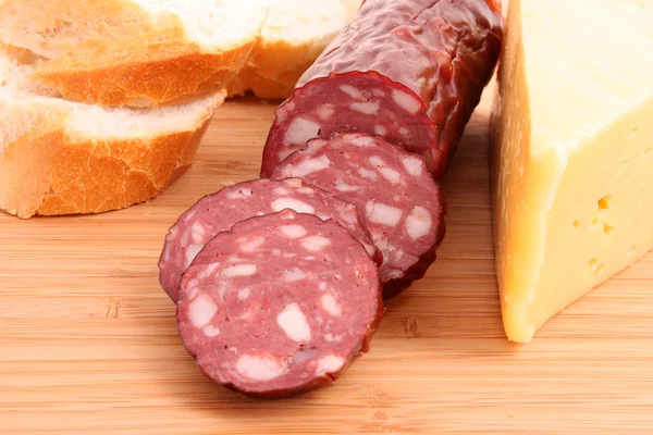 Sausage and bread on wooden surface — Stock Photo, Image