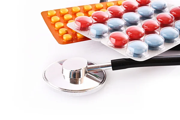 Tabletten und Stethoskop isoliert auf weiß — Stockfoto