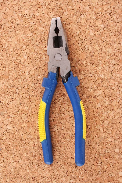 Pliers on cork board surface — Stock Photo, Image