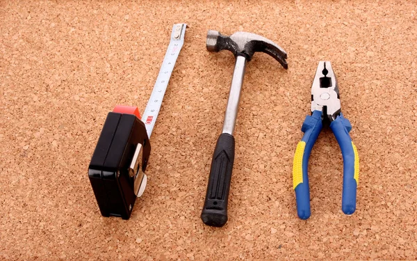 Hammer, pliers and ruller on cork board surface — Stock Photo, Image
