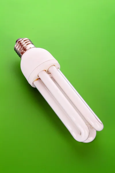 Энергосберегающая лампочка на зеленом — стоковое фото