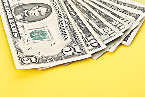 Few dollar banknotes on yellow background — Stock Photo, Image