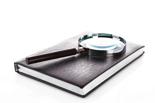 Notebook with a magnifier on it isolated on white — Stock Photo, Image