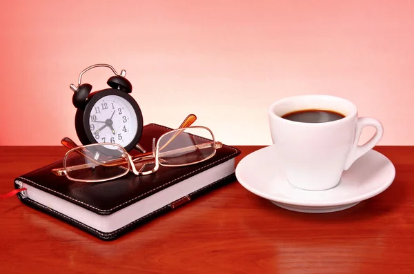 Filiżankę kawy, książki, zegar i kalkulator na drewnianym stole — Zdjęcie stockowe
