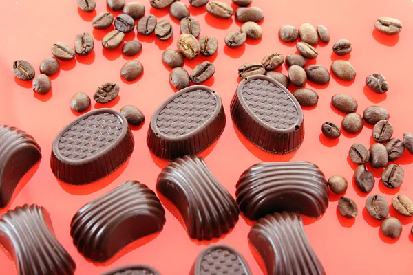 Choklad och kaffe bönor på röd bakgrund — Stockfoto
