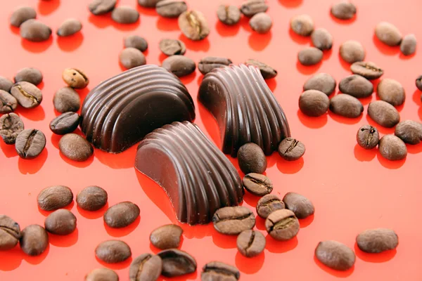 Chocolate and coffee beans on red background — Stock Photo, Image