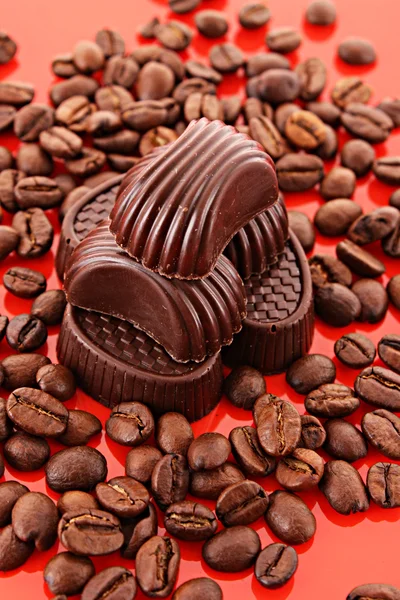 Schokolade und Kaffeebohnen auf rotem Hintergrund — Stockfoto