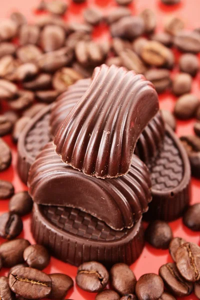 Chocolate y granos de café sobre fondo rojo — Foto de Stock