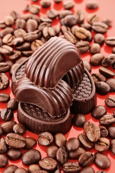 Coklat dan kopi kacang pada latar belakang merah — Stok Foto