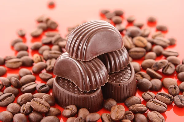 Grãos de chocolate e café no fundo vermelho — Fotografia de Stock