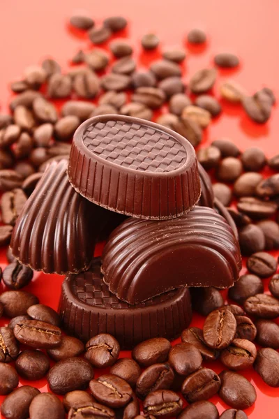 Σοκολάτα και καφέ φασόλια σε κόκκινο φόντο — Φωτογραφία Αρχείου