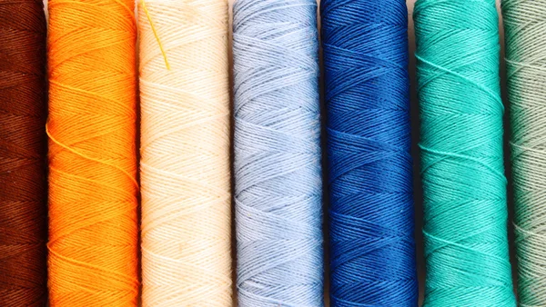 Pile of coloured bobbins of lurex thread isolated on white — Stock Photo, Image