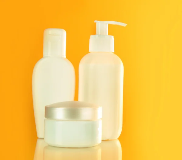 Bottles of health and beauty products on yellow background — Stock Photo, Image