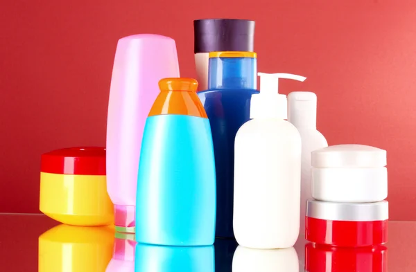 Bottles of health and beauty products on red background — Stock Photo, Image