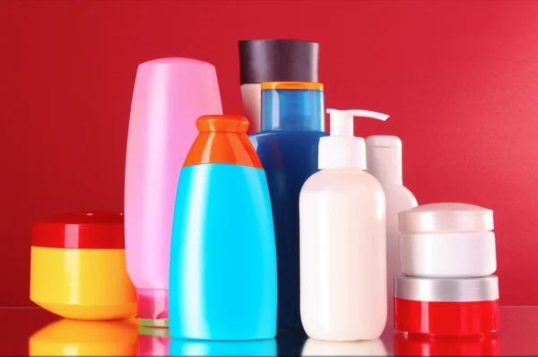 Bottles of health and beauty products on red background — Stock Photo, Image