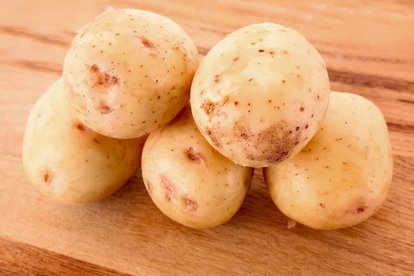 Poucas batatas na superfície de madeira — Fotografia de Stock