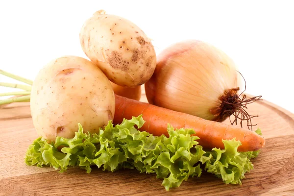 Lök, morot och potatis på träplatta — Stockfoto
