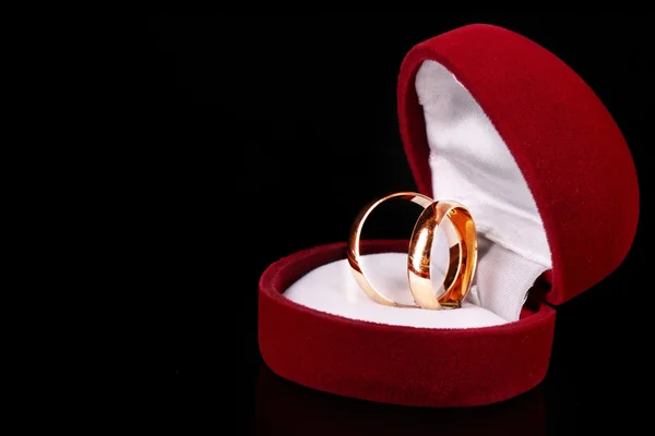 Anéis de casamento dourados em caixa vermelha isolada em preto — Fotografia de Stock