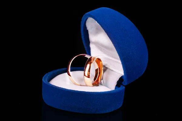 Anéis de casamento dourados em caixa azul isolado em preto — Fotografia de Stock