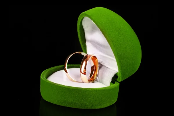 Anéis de casamento dourados em caixa verde isolado em preto — Fotografia de Stock