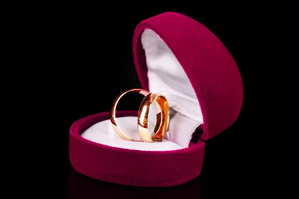 Anéis de casamento dourados em caixa rosa isolado em preto — Fotografia de Stock