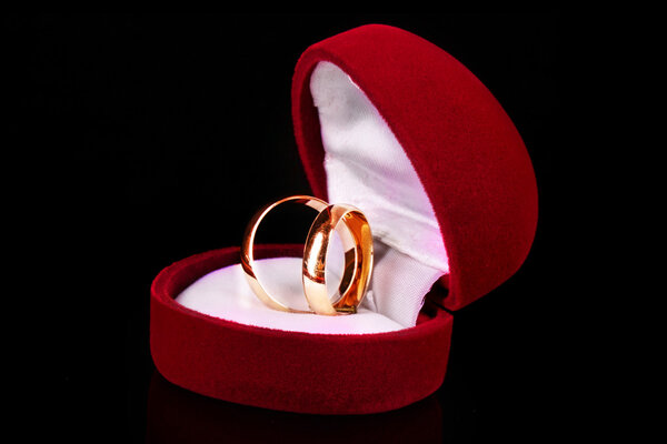 Golden wedding rings in red box isolated on black