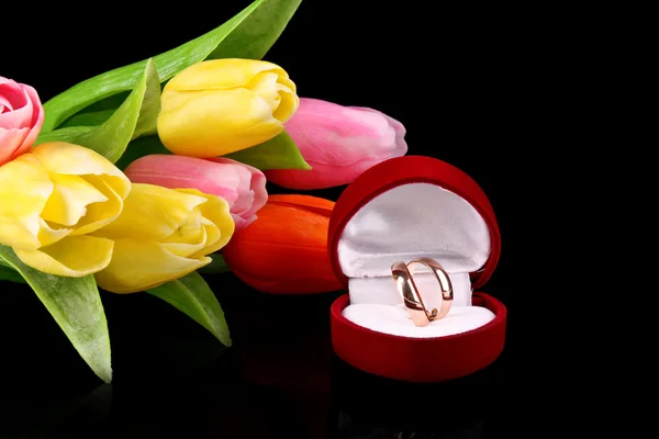 Zlaté prsteny a tulipány na černém pozadí — Stock fotografie